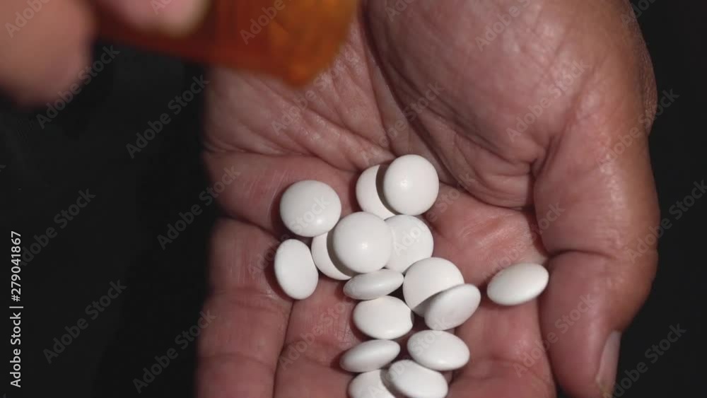 Old woman pours pills vitamins or drugs tablets in hand from pill bottle, slow motion Old woman pours pills vitamins or drugs tablets in hand from pill bottle, slow motion