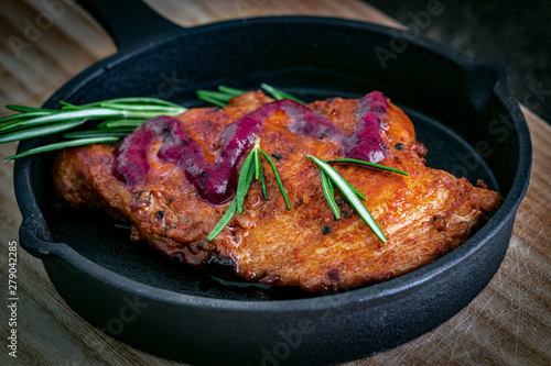 Fried chicken fillet in a paprika marinade with wild berry sauce and a sprig of rosemary.