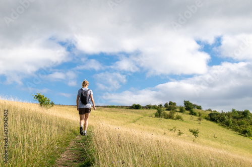 Woman hiking on a field on the Cotswold Way, Gloucestershire, England