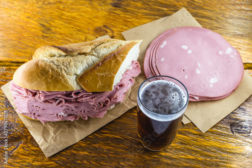 Bread snack with mortadella on a rustic empress table, with typical Brazilian beer. photo