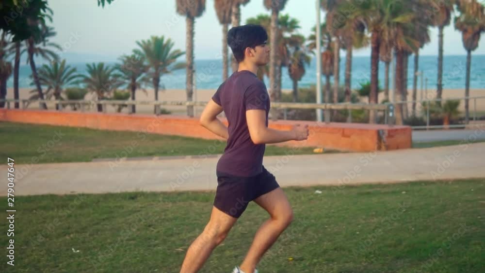 Young athletic man running at palm tree park near the beach. Urban run Young athletic man running at palm tree park near the beach. Urban run