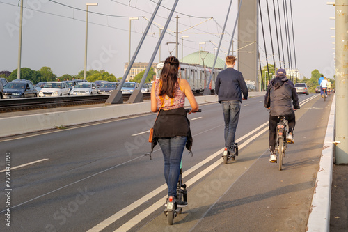 People ride E-scooters, trendy urban transportation with Eco friendly sharing mobility concept, on bicycle lane to avoid traffic jam on the bridge cross Rhine River in Düsseldorf, Germany. photo