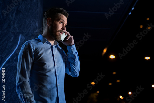 Handsome young businessman talking on phone at night