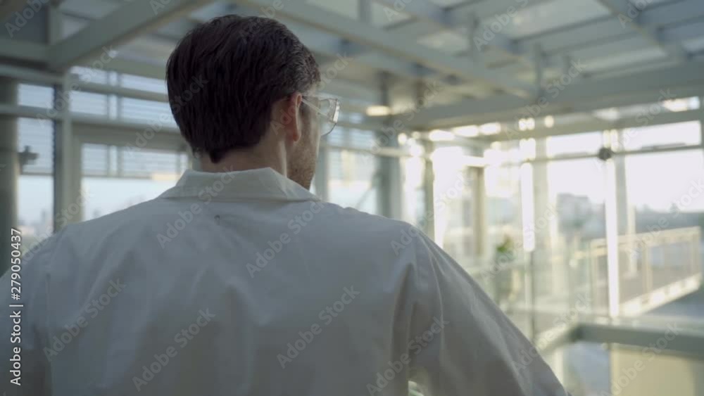 Biotech scientist or doctor in a hospital or lab stands and looks at the horizon Biotech scientist or doctor in a hospital or lab stands and looks at the horizon