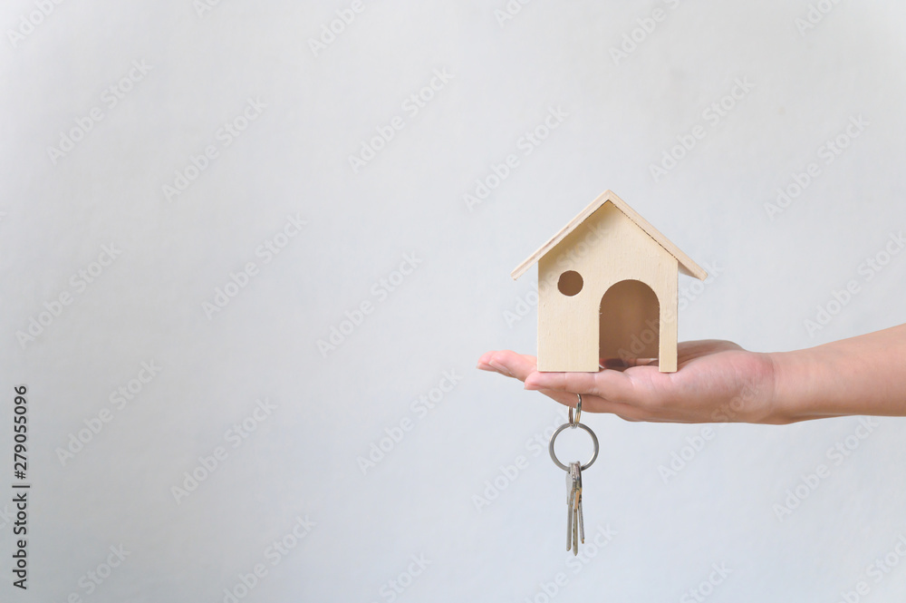 Hand holding wooden house and home keychain. Property investment and house mortgage financial real estate concept Hand holding wooden house and home keychain. Property investment and house mortgage financial real estate concept