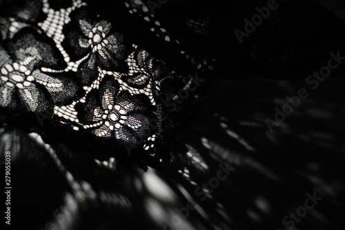 Abstract background of shadows black floral laces on white table. Light going through black lace. Romantic, passion background for sites, flyers, package