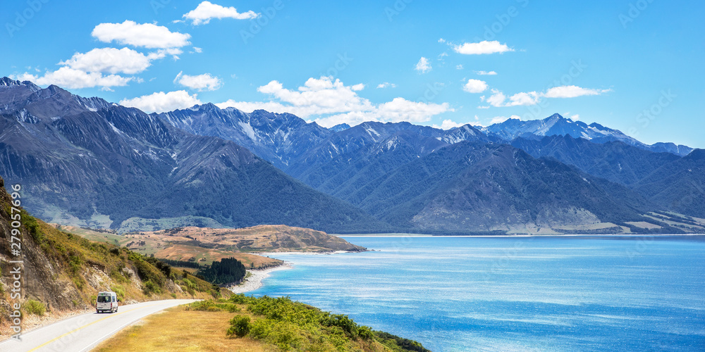 Travel van car driving on road near lake in mountains Travel van car driving on road near lake in mountains