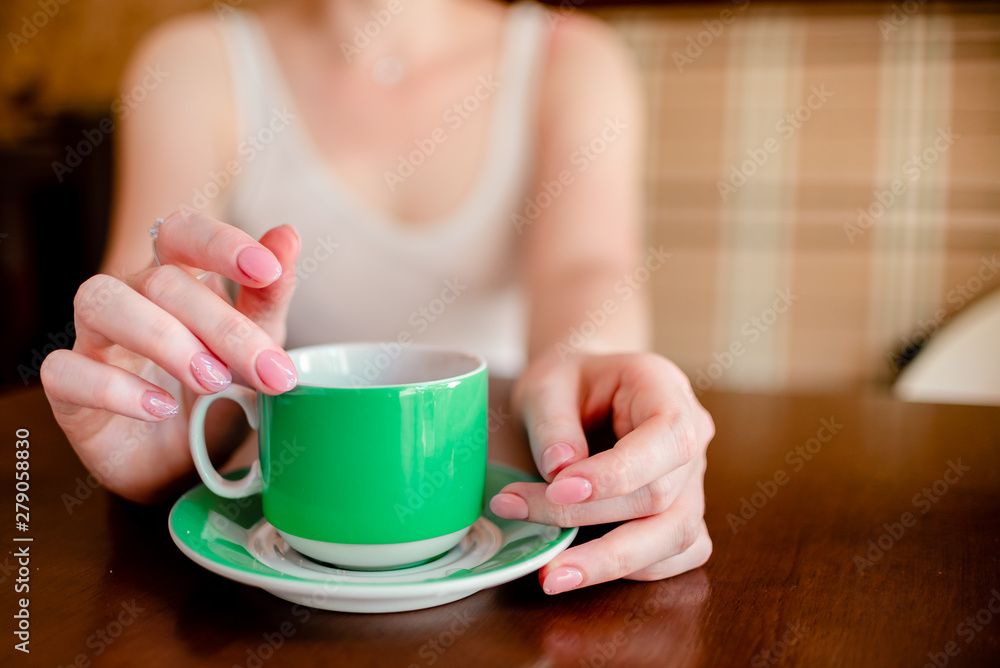 Female hands hold hot green coffee cup beverage, drinks cappuccino. Horizontal several objects copyspace Female hands hold hot green coffee cup beverage, drinks cappuccino. Horizontal several objects copyspace