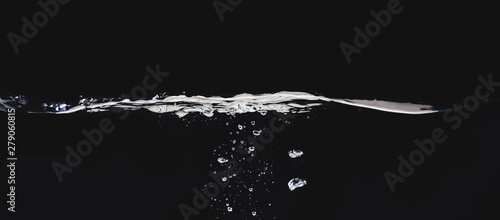 Waving liquid surface isolated on black background, close up view. Small water bubbles underwater. Black abstract background for overlays design, screen blending mode layer