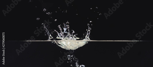 Water splash on liquid surface isolated on black background, close up view. Water bubbles in air, abstract black background for overlays design, screen blending mode layer
