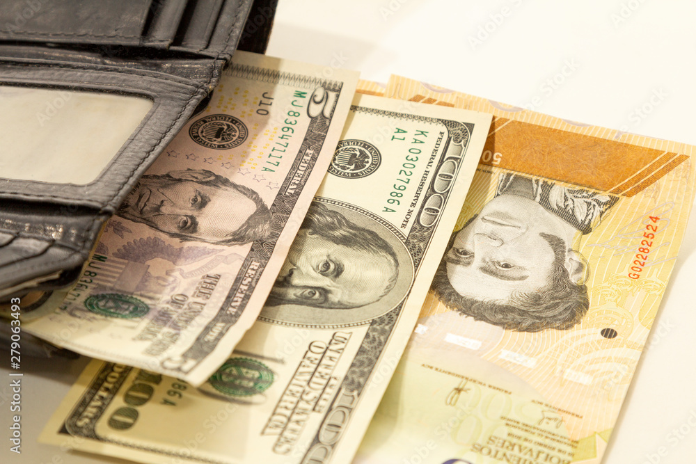 Black leather wallet with Venezuelan money bolivars and US dollar currency. Black leather wallet with Venezuelan money bolivars and US dollar currency.