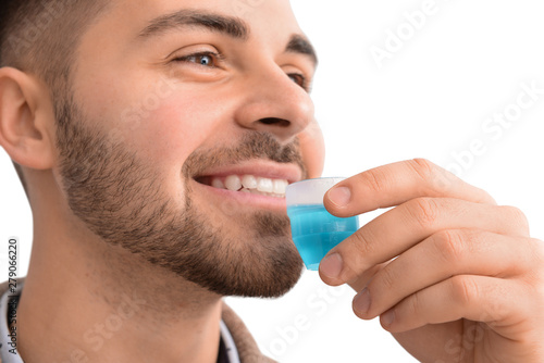 Handsome man with mouthwash on light background, closeup