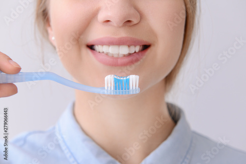 Woman with toothbrush on light background, closeup. Concept of dental hygiene