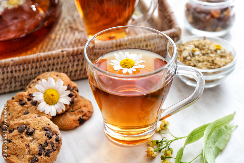 Cup of tasty chamomile tea with cookies on light table Cup of tasty chamomile tea with cookies on light table