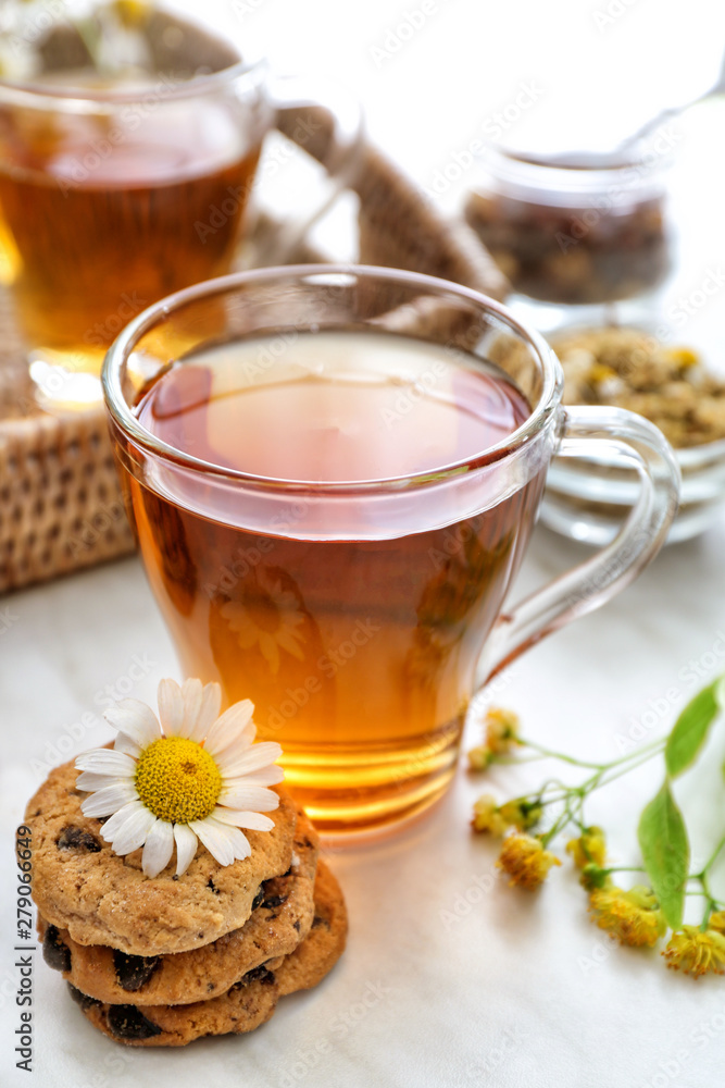 Cup of tasty chamomile tea with cookies on light table Cup of tasty chamomile tea with cookies on light table