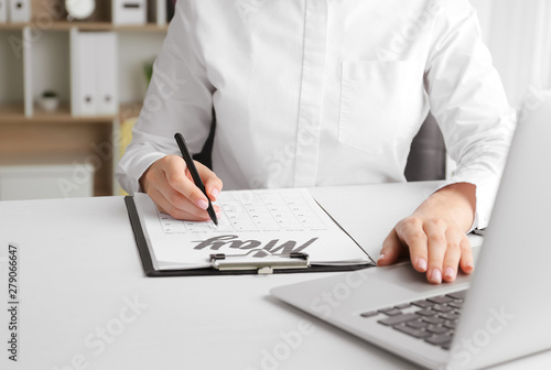 Young woman marking date in calendar at table  closeup