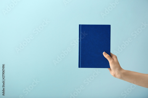 Female hand with book on color background