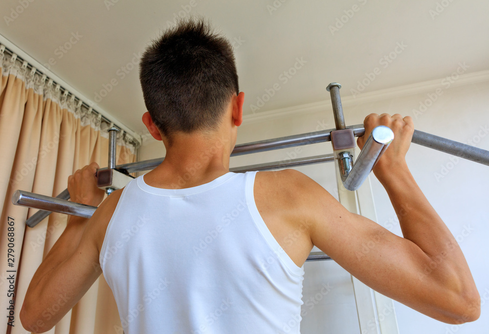 Teen doing exercises on the crossbar in the home sports corner. Stock ...