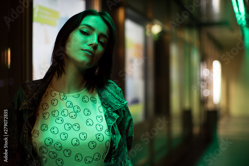 Beautiful girl street portrait. Green Neon light, she's wearing an alien shirt photo