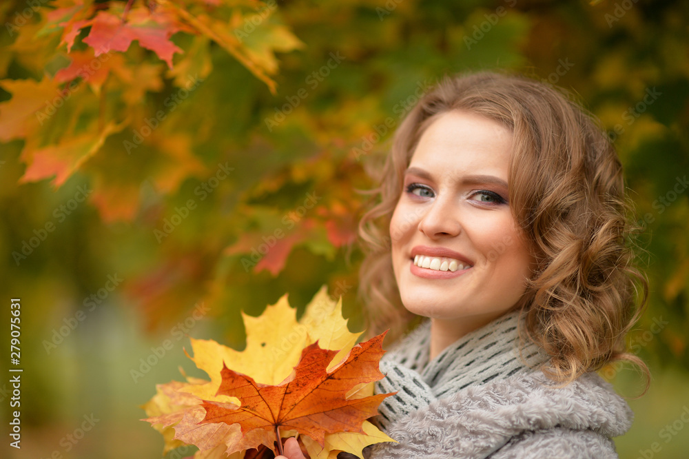 Portrait of beautiful young woman holding autumn leaves