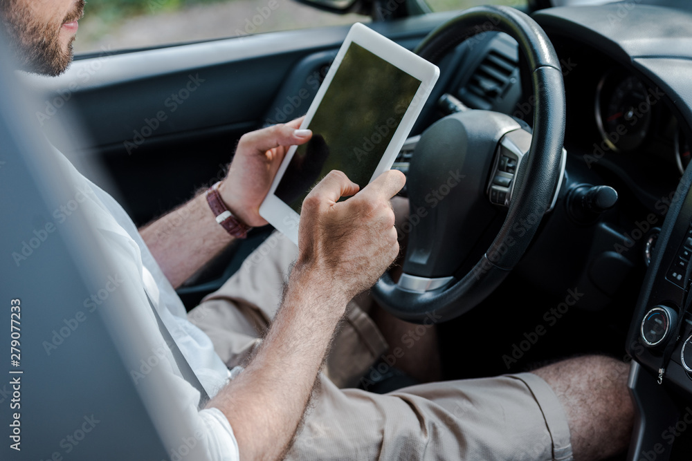 cropped view of man sitting in car and using digital tablet
