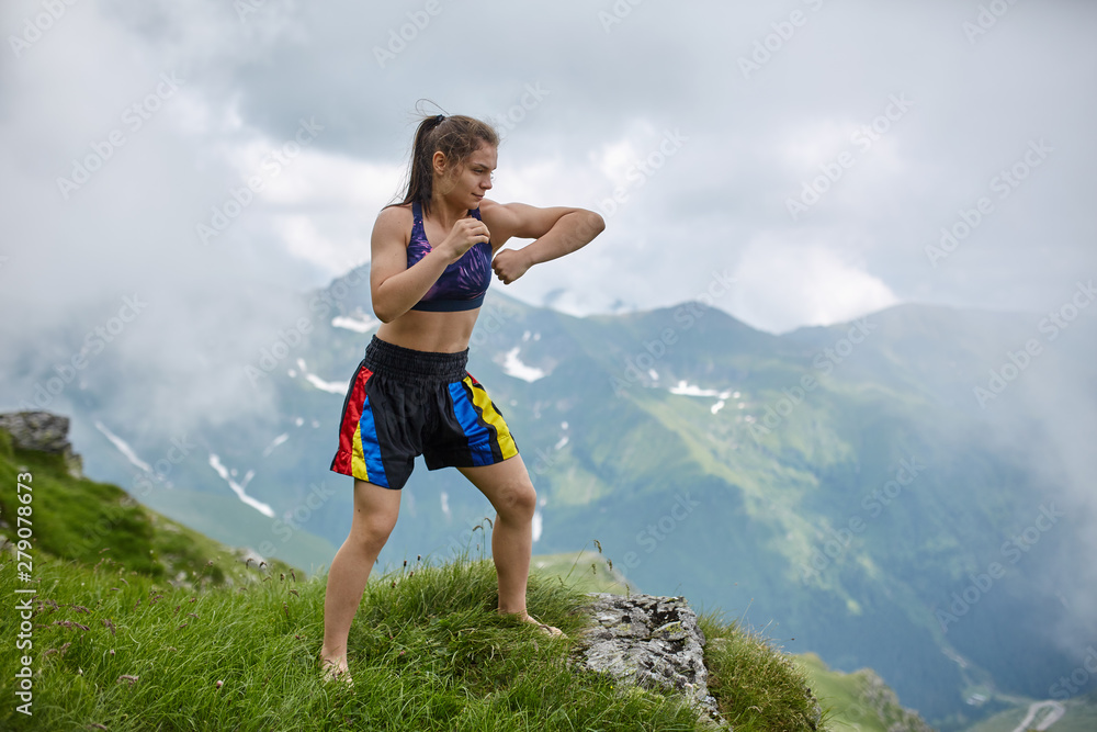 Naklejka premium Kickboxing girl on the mountains
