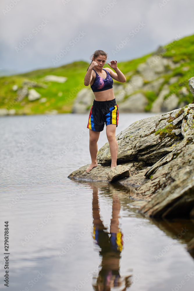 Woman kickbox fighter training by the lake Woman kickbox fighter training by the lake