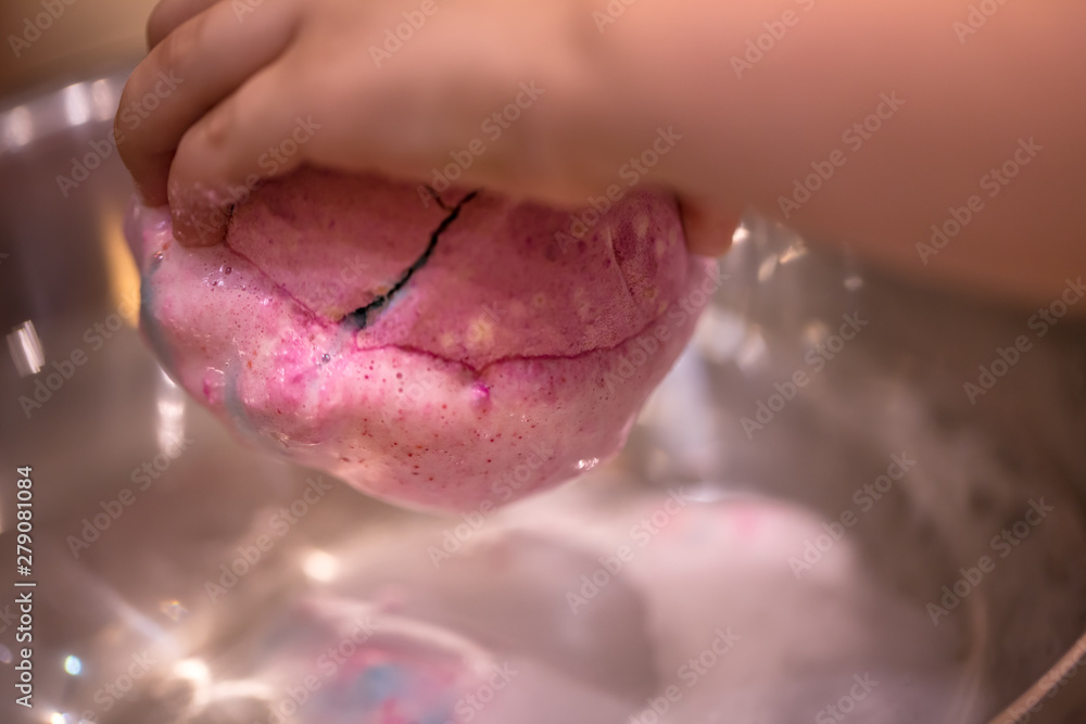 Fototapeta premium Bright natural fizzy bath bomb dissolves in the hands