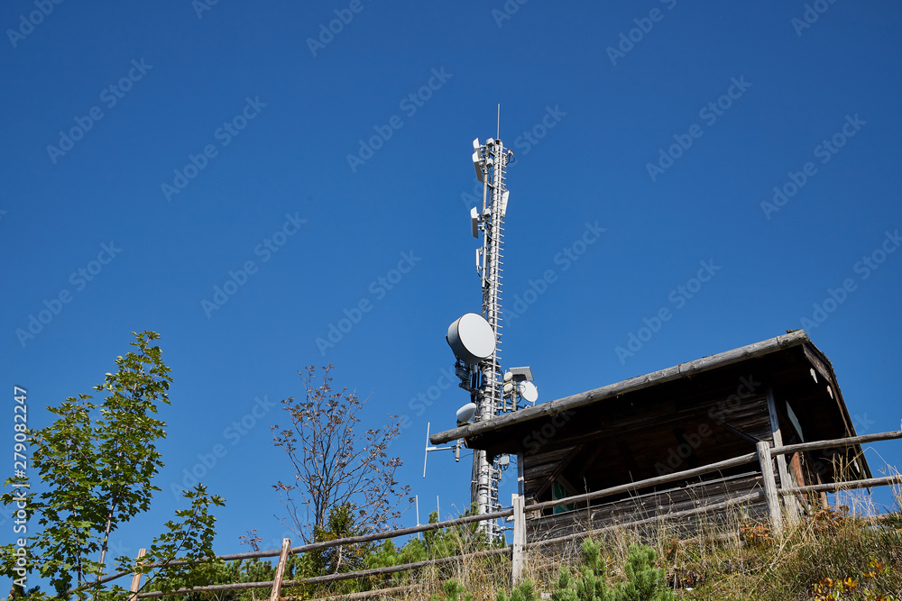 Cell tower at the top of the mountain among the greenery on a summer day