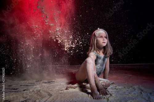 Small girl during photoshoot with flour in dark studio