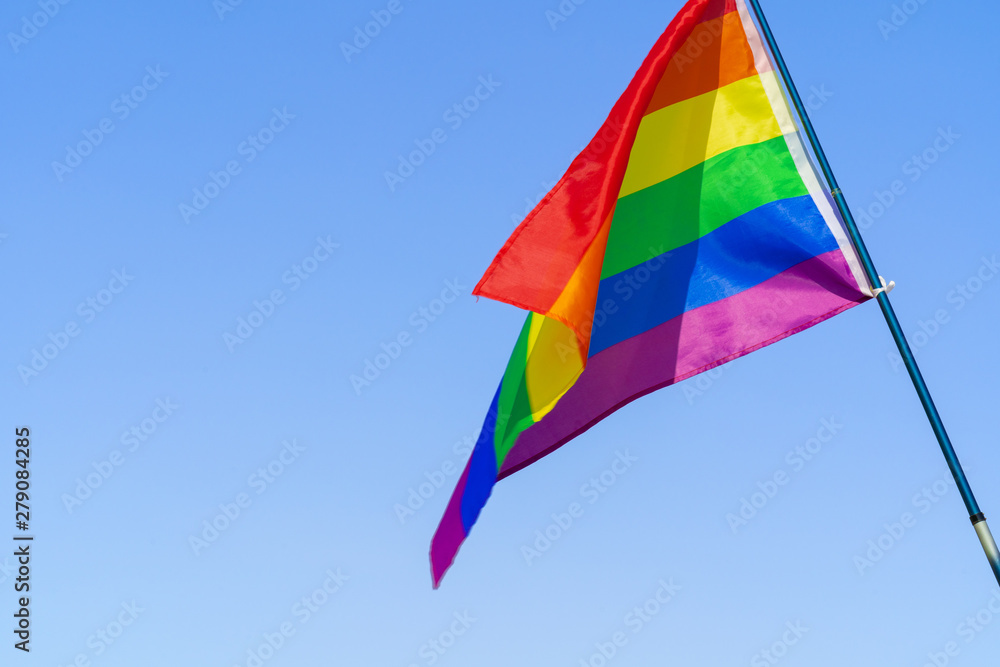 LGBT waving flag in the sky on flagpole LGBT waving flag in the sky on flagpole