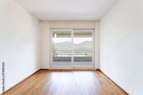 Bedroom with white walls and parquet. Window with lake view.
