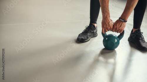 Cropped photo of strong man holding big black dumbbell while doing weight exercises at gym