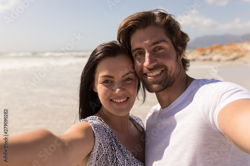 Happy young couple looking at camera on beach