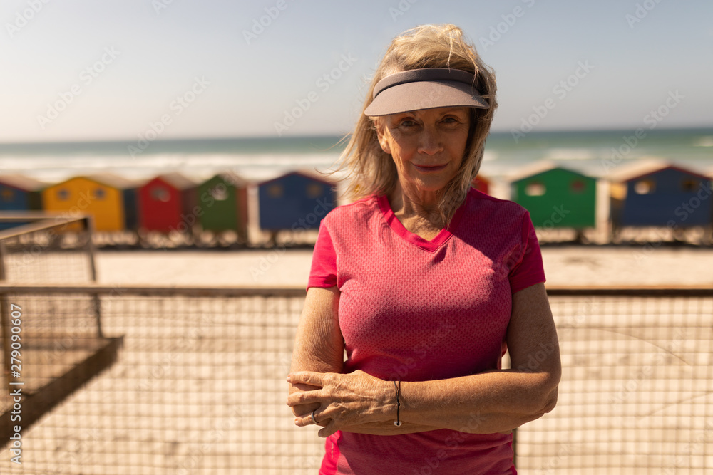 Senior woman standing with arms crossed on promenade at beach