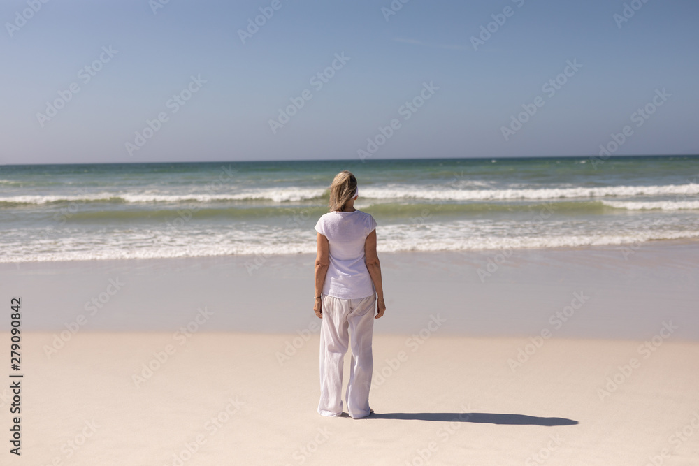 Rear view of senior woman standing on the beach Rear view of senior woman standing on the beach