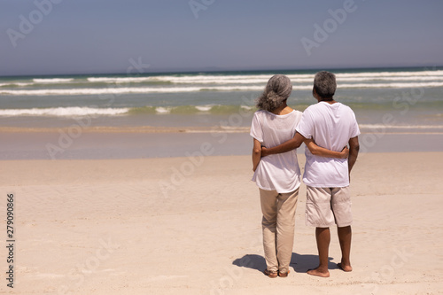 Senior couple standing on a beach with their arms around each other