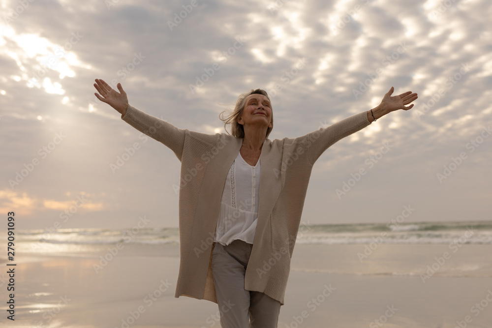 Senior woman standing with arms outstretched on the beach Senior woman standing with arms outstretched on the beach