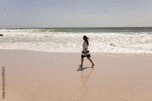 Young woman walking on beach and looking at the horizon