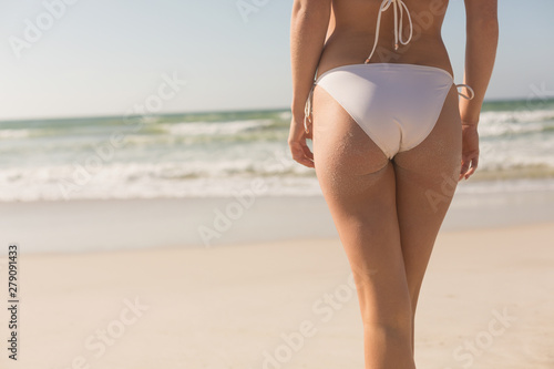 Young Caucasian woman in bikini standing on the beach