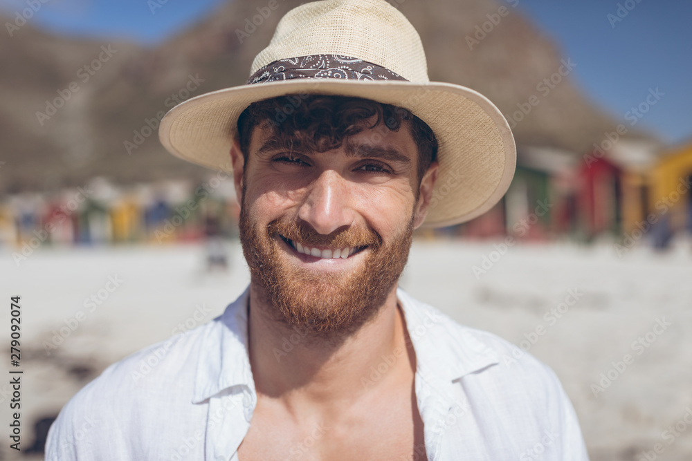 Happy man looking and smiling at camera standing at beach 