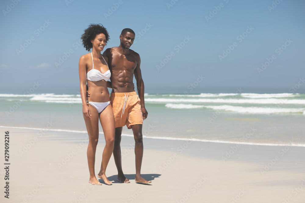 Couple walking with arm around at beach Couple walking with arm around at beach