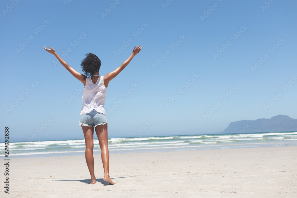 Beautiful woman standing with open arm at beach on sunny day Beautiful woman standing with open arm at beach on sunny day
