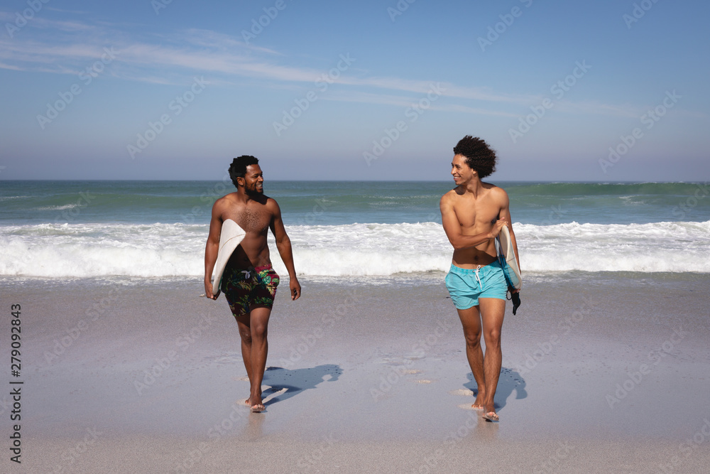 Young men with surfboard walking at beach in the sunshine Young men with surfboard walking at beach in the sunshine