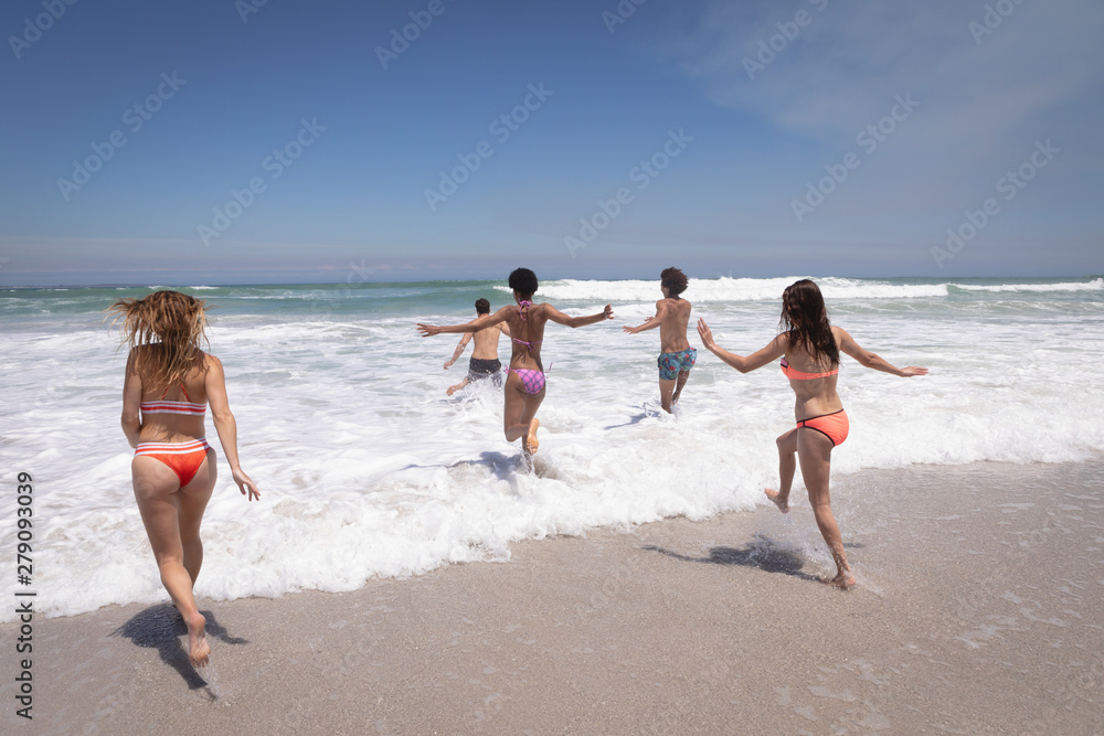 Fototapeta premium Group of friends running in ocean waves
