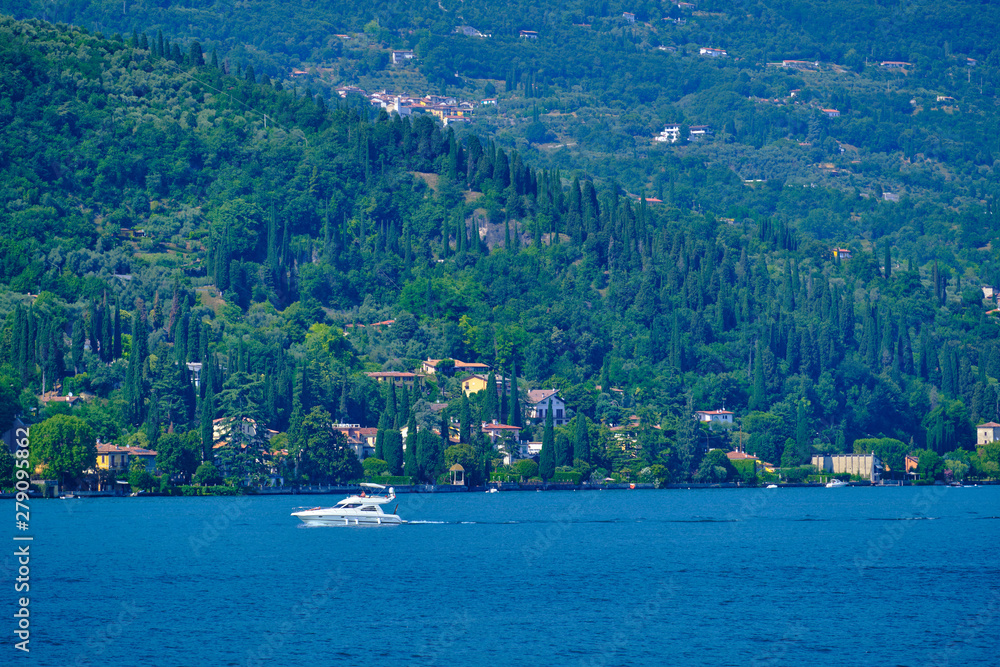 White yacht at high speed moves against the backdrop of a resort town in Italy