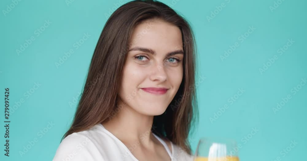 Beautiful girl drinks cold water with a yellow lemon. lemonade in a wine glass. Summer drink. Slow motion. Turquoise background. Beautiful girl drinks cold water with a yellow lemon. lemonade in a wine glass. Summer drink. Slow motion. Turquoise background.