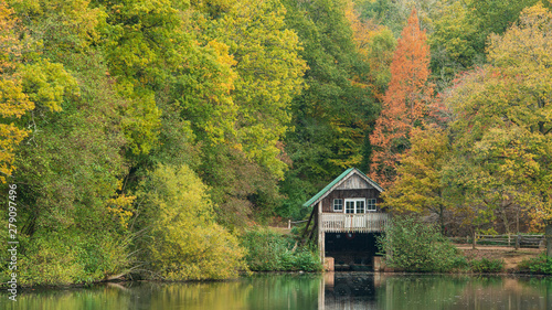 Stunning colorful vibrant Autumn Fall landscape image of boathouse on lake in forest scene
