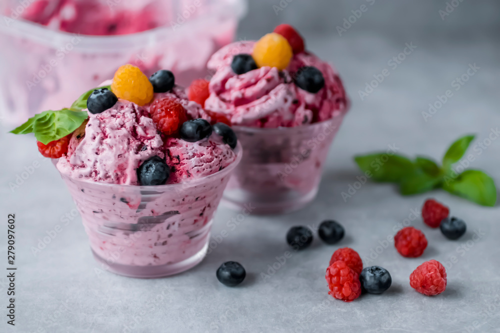 Homemade ice cream made from fresh berries with basil in glass bowl on a gray background. Homemade ice cream made from fresh berries with basil in glass bowl on a gray background.