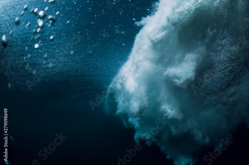 Barrel wave underwater with air bubbles and sun light. Ocean in underwater